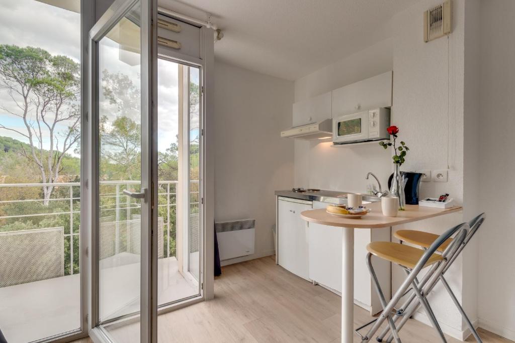 a kitchen with a table and chairs and a balcony at City Résidence Sophia in Valbonne