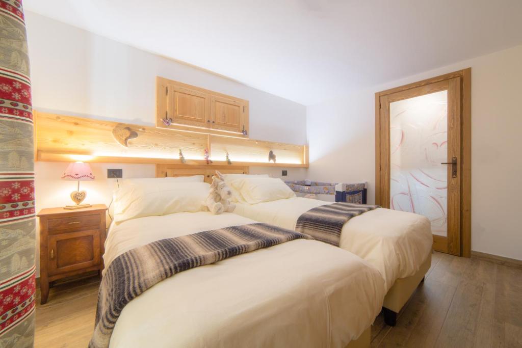 1 dormitorio con 2 camas y puerta con ventana en Maison Julie-lungo la via Francigena, en Etroubles