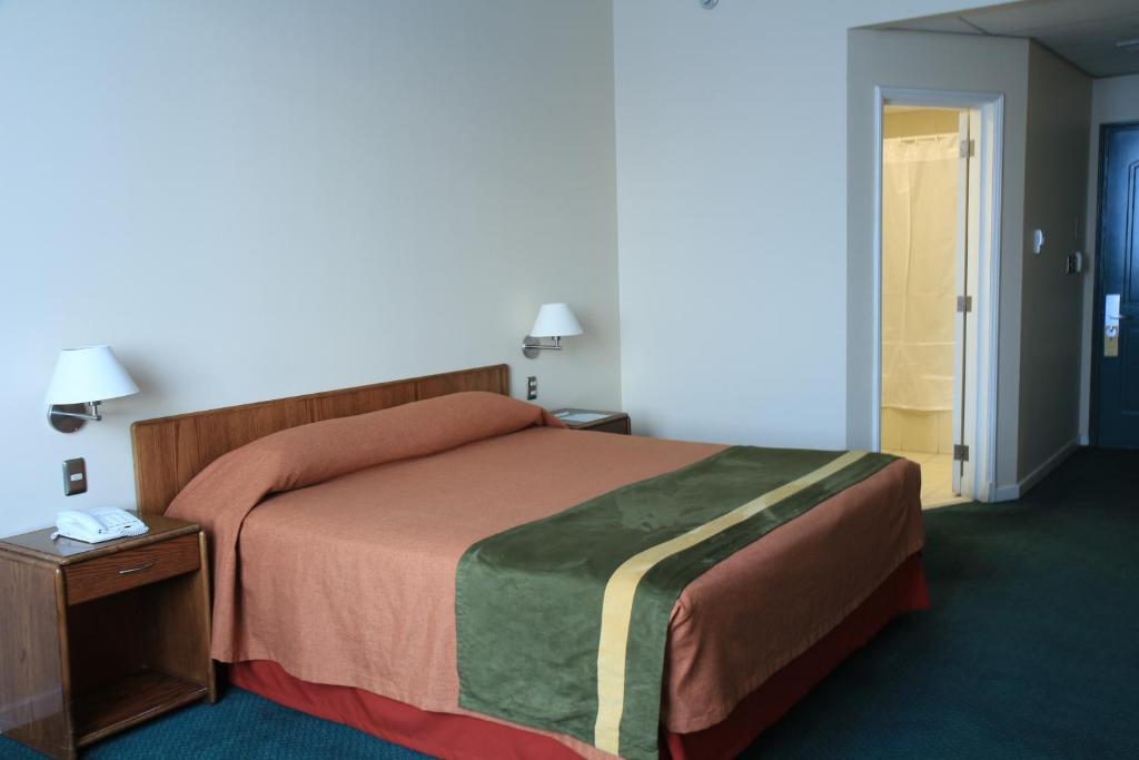 a hotel room with a bed and a night stand at Hotel Diego de Almagro Aeropuerto in Santiago