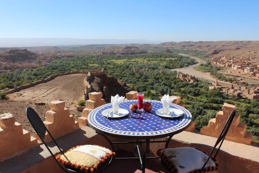 a table and chairs sitting on the edge of a mountain at Dar Timitar in El Kelaa des Mgouna
