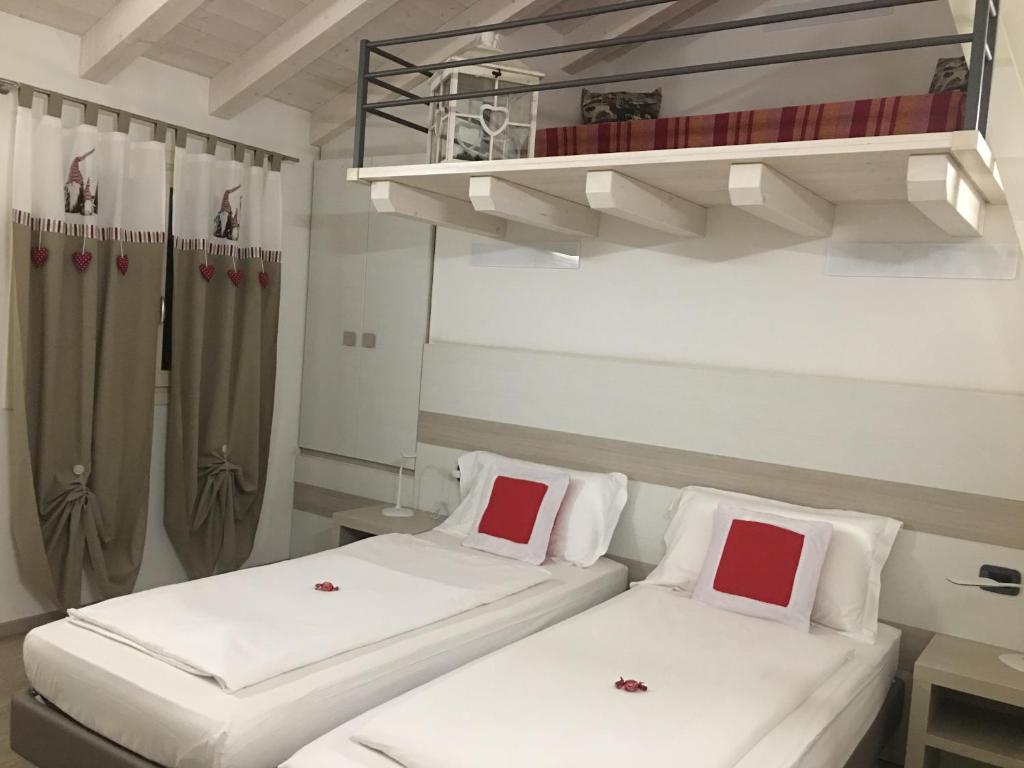 2 bedden in een kamer met witte en rode kussens bij B&B Nuova Ostiglia in Quinto di Treviso