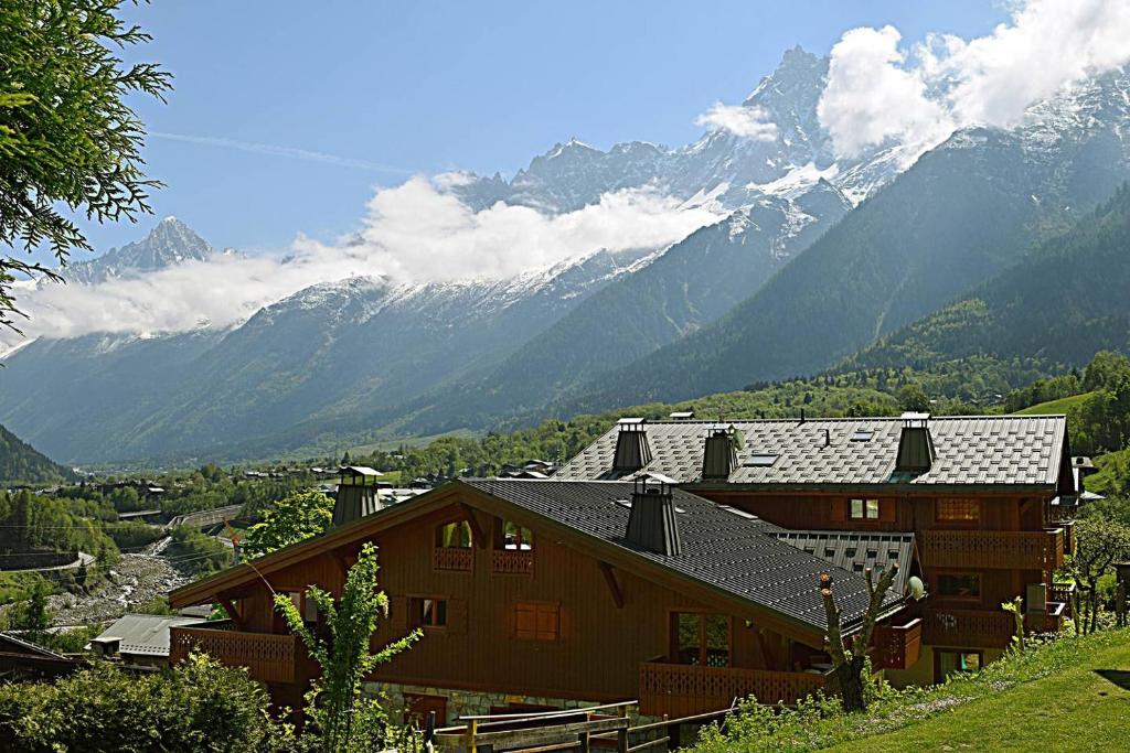 uma casa numa colina com montanhas ao fundo em Spacious Apartment 2 Minutes from Ski Lift, Equipped for Babies em Les Houches