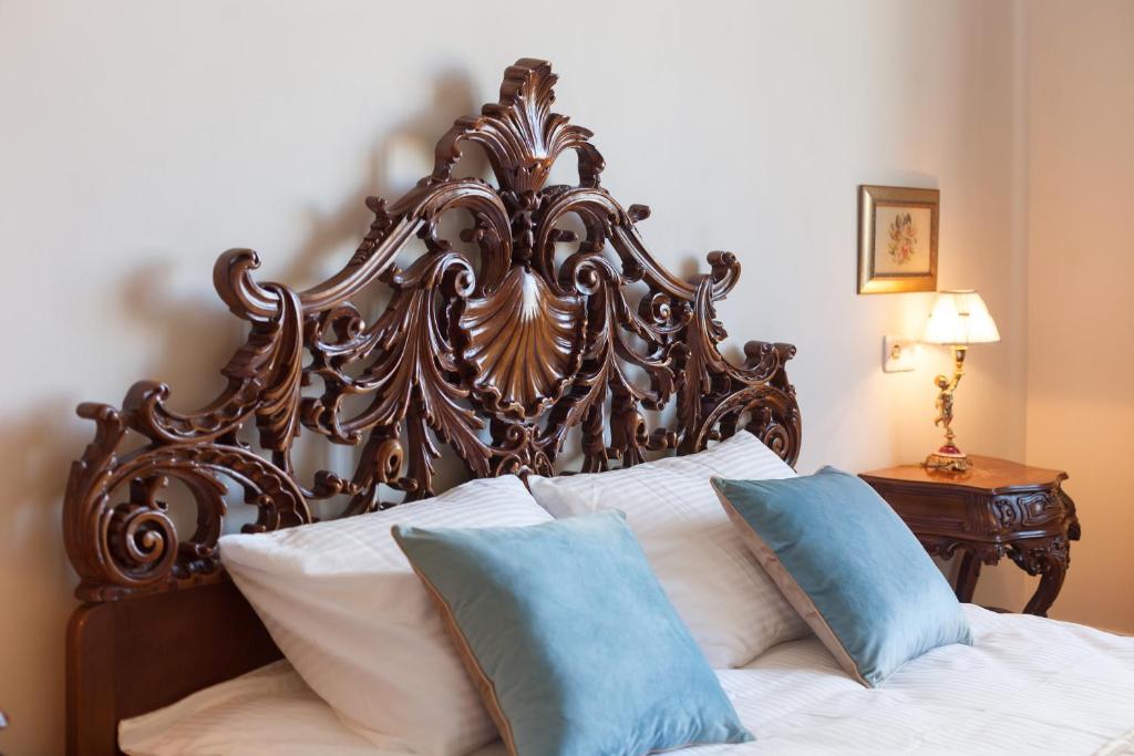 a bed with an ornate wooden headboard and pillows at LUXOVSKI apartment in Lviv
