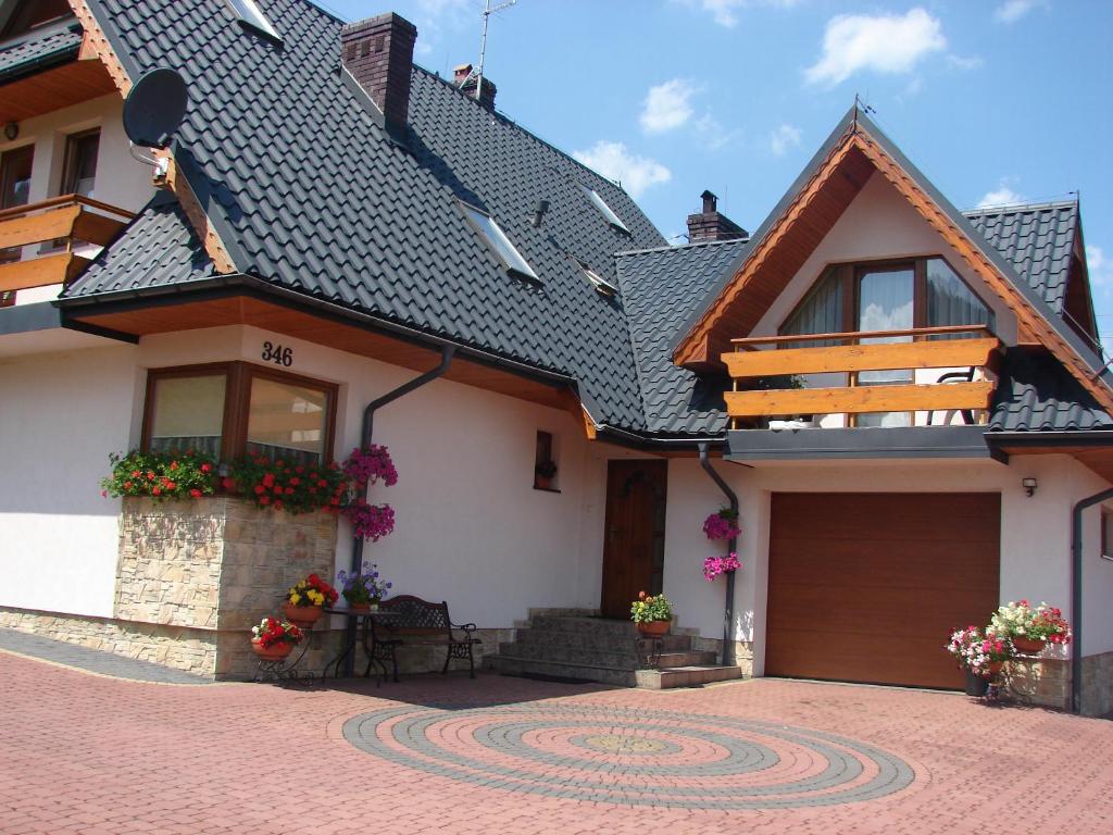 une maison blanche avec un toit noir et une allée. dans l'établissement Pokoje u Ewy, à Kościelisko