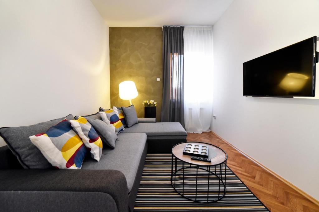een woonkamer met een bank en een tv bij Corner Apartments Savska in Zagreb