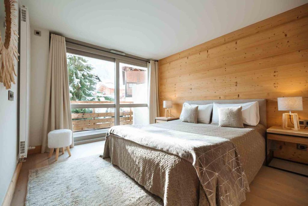 um quarto com uma cama e uma grande janela em Mègeve - Luxury appartment – AE302 em Megève