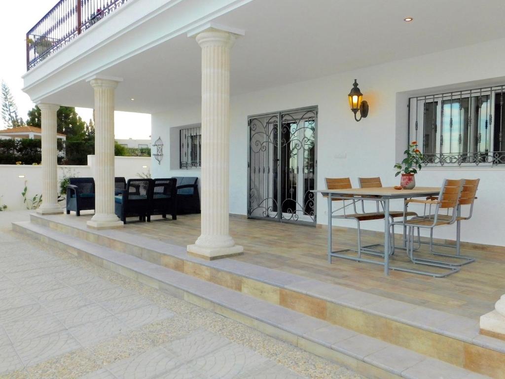 une véranda avec colonnes, table et chaises dans l'établissement Maison Al Riad, à Mojácar