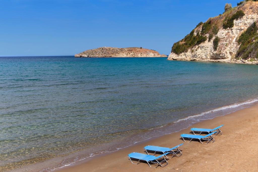 two blue beach chairs on a beach with the ocean at Kastro Kera in Almirida