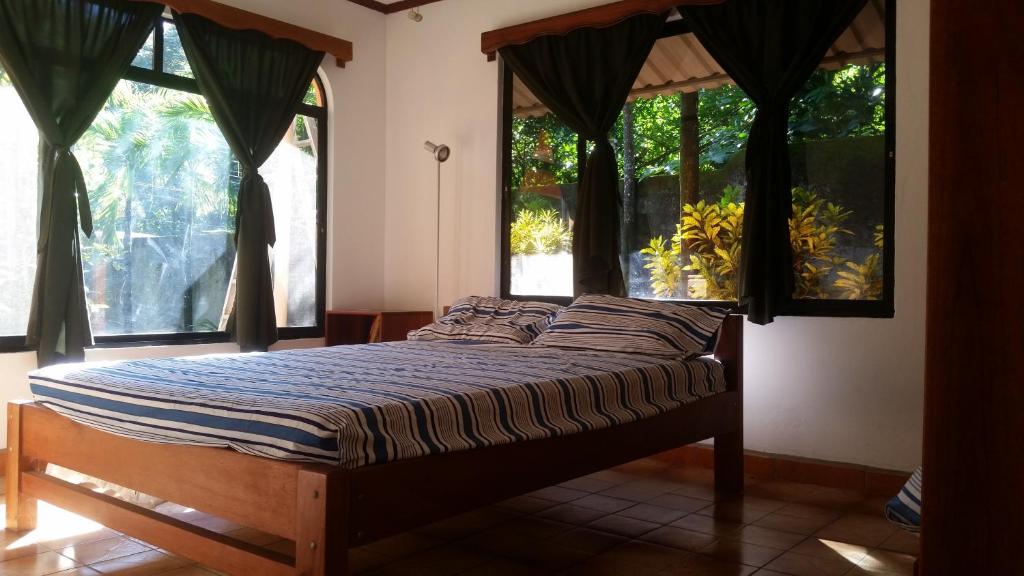 1 cama en una habitación con ventanas en un dormitorio en Embassy House, en Puerto Jiménez