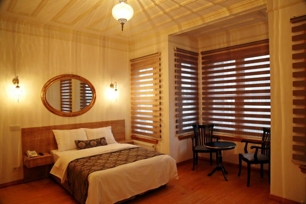 Schlafzimmer mit einem Bett, einem Tisch und einem Spiegel in der Unterkunft Belizia Hotel in Istanbul