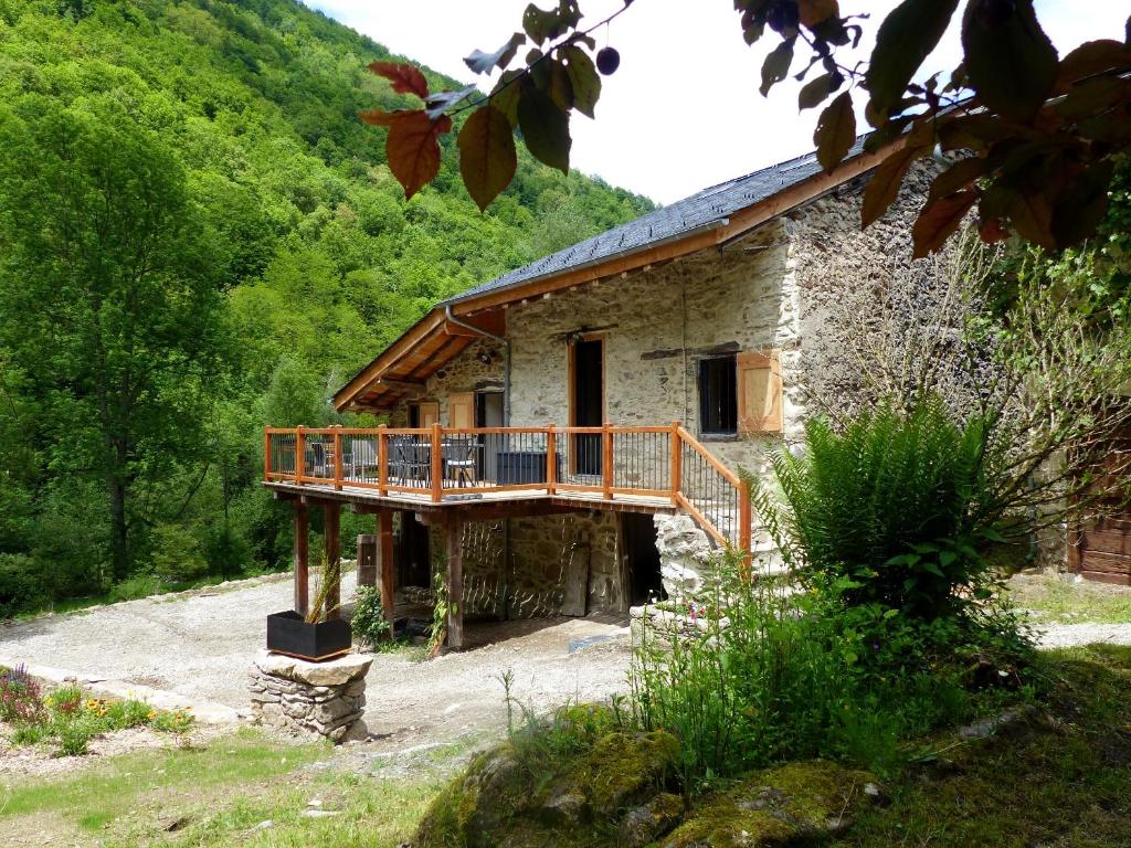 une maison en pierre avec une terrasse en bois devant elle dans l'établissement la grange de clotilde, à Siguer