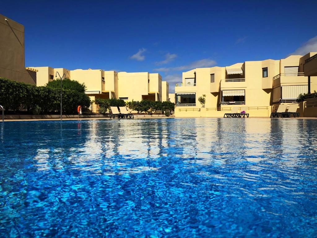 a large swimming pool with blue water in front of buildings at Villa Ocean Beach in El Médano