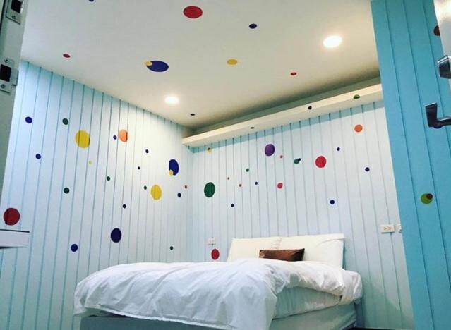 Un dormitorio con una pared con bolas de colores. en Peacock hotel en Daxi