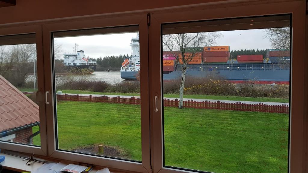 une fenêtre avec vue sur un navire dans l'eau dans l'établissement Ferienwohnung mit wunderschönem Blick auf den Nord-Ostsee-Kanal, à Breiholz