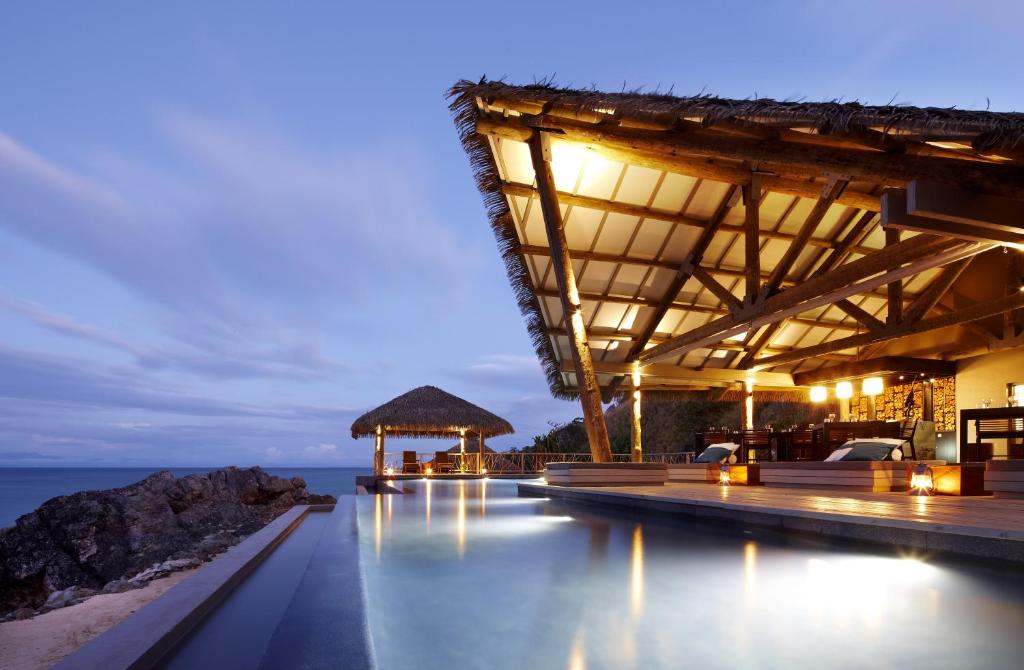 a resort with a pool and the ocean at night at Tadrai Island Resort in Mana Island