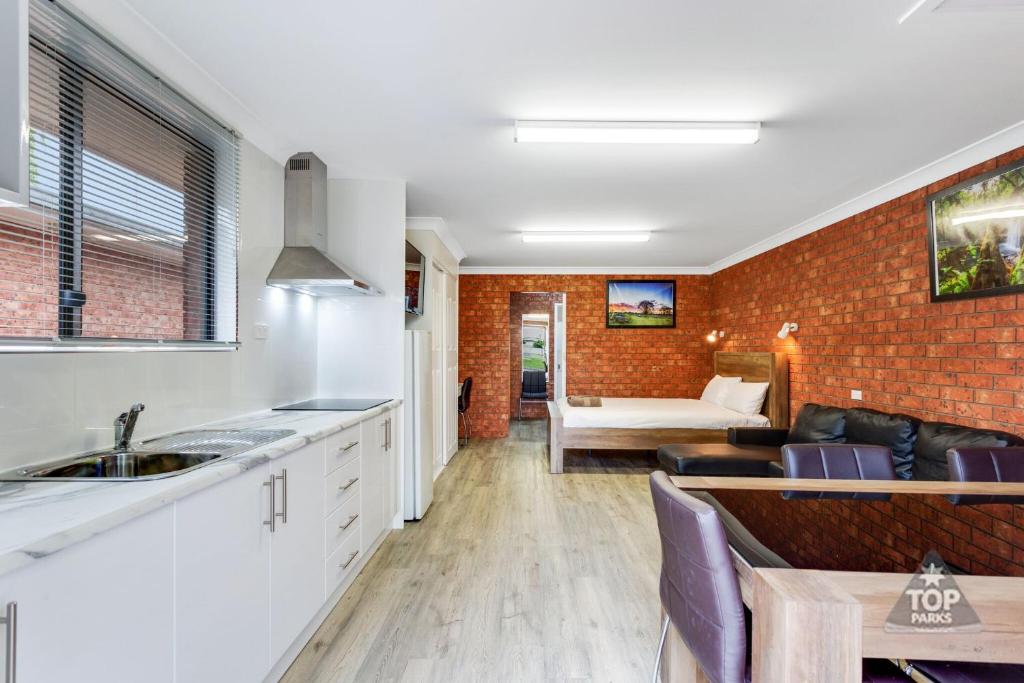 a kitchen and living room with a brick wall at Fossicker Caravan Park in Glen Innes