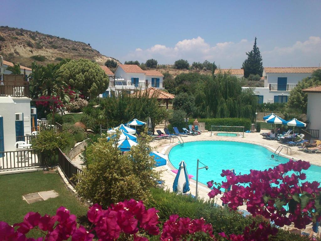 a view of a swimming pool with pink flowers at Hylatio Tourist Village in Pissouri