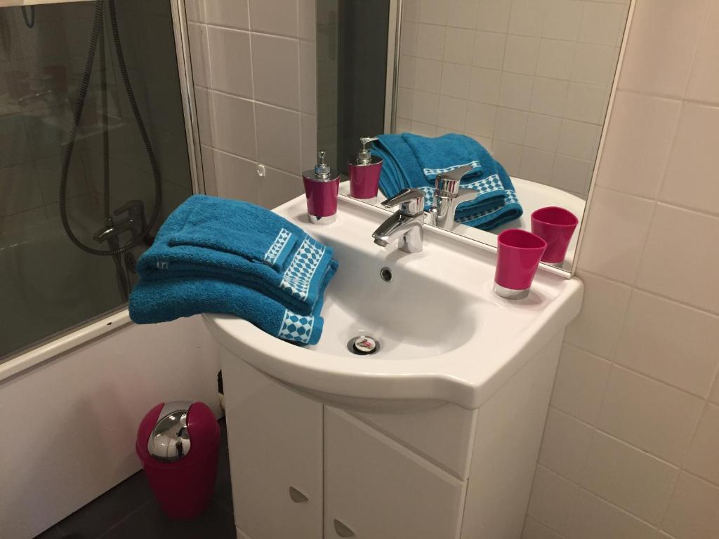 a bathroom sink with two cups and a blue towel at Appartement Le Grand Parc in Châteauroux