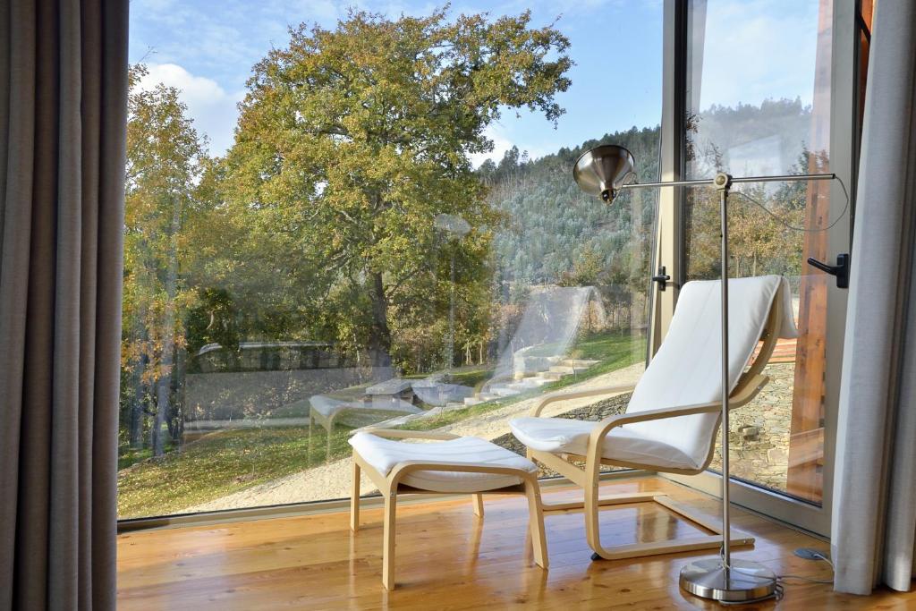 Cette chambre dispose d'une grande fenêtre avec deux chaises et une lampe. dans l'établissement Quinta da Longra, à Alvarenga