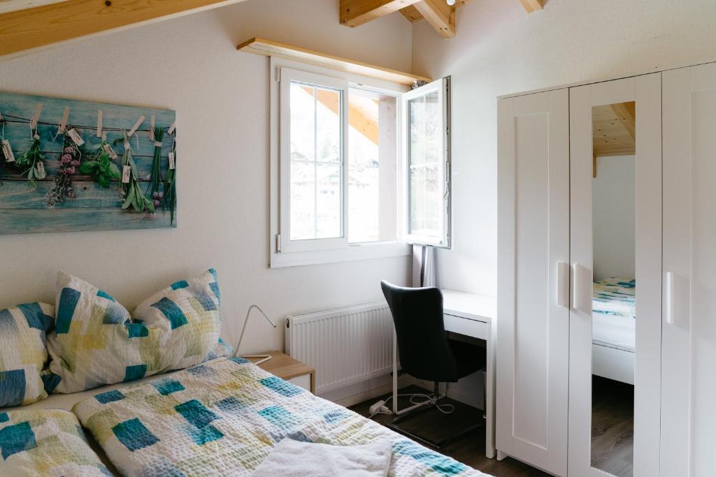Schlafzimmer mit einem Bett, einem Schreibtisch und einem Fenster in der Unterkunft Wetterhorn, Eiger, Jungfrau, Amazing! in Grindelwald