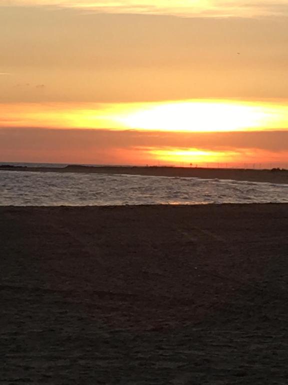 a sunset on the beach with the ocean at Brookfield’s Apartment in Clacton-on-Sea