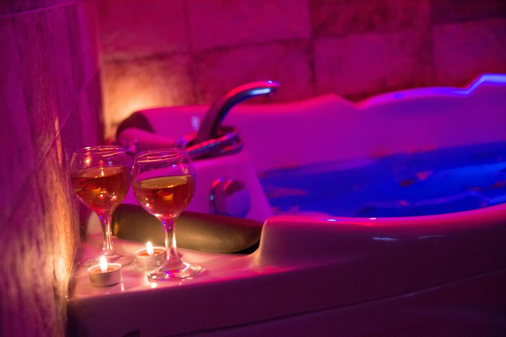 dois copos de vinho sentados numa saliência ao lado de uma banheira em Wonderland spa apartment em Niš