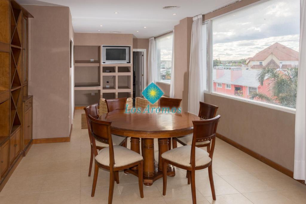 ein Esszimmer mit einem Tisch, Stühlen und einem Fenster in der Unterkunft Los Aromos Apart Spa in Las Grutas