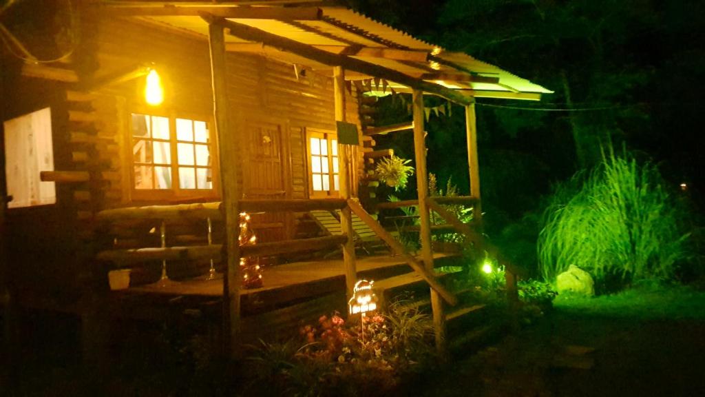 Cabaña de madera con porche por la noche en Cabaña Alamos Altos en Belén de Escobar