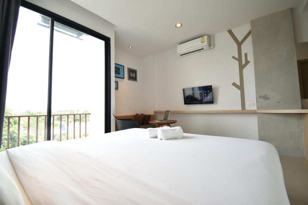 ein Schlafzimmer mit einem großen weißen Bett und einem Fenster in der Unterkunft B Boutique Hotel in Surat Thani