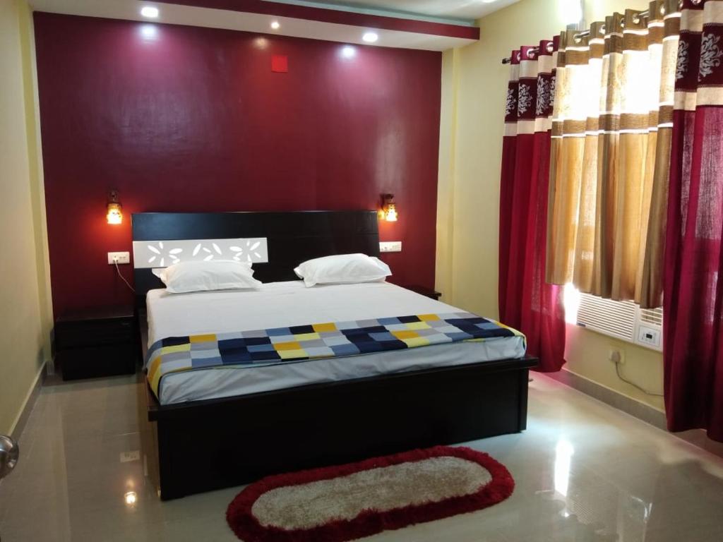 um quarto com uma cama grande e uma parede vermelha em Shonar Kutir em Puri
