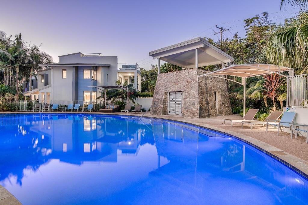 a swimming pool in front of a house at Coolum At The Beach in Coolum Beach