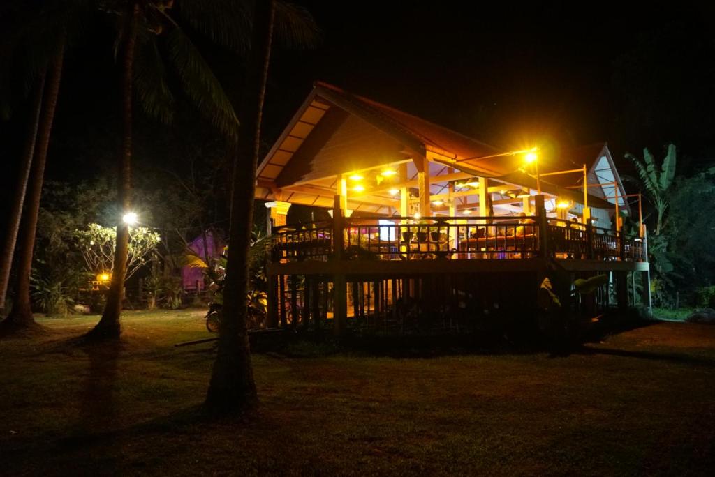 a building with a deck at night with lights at The Boathouse in Don Det