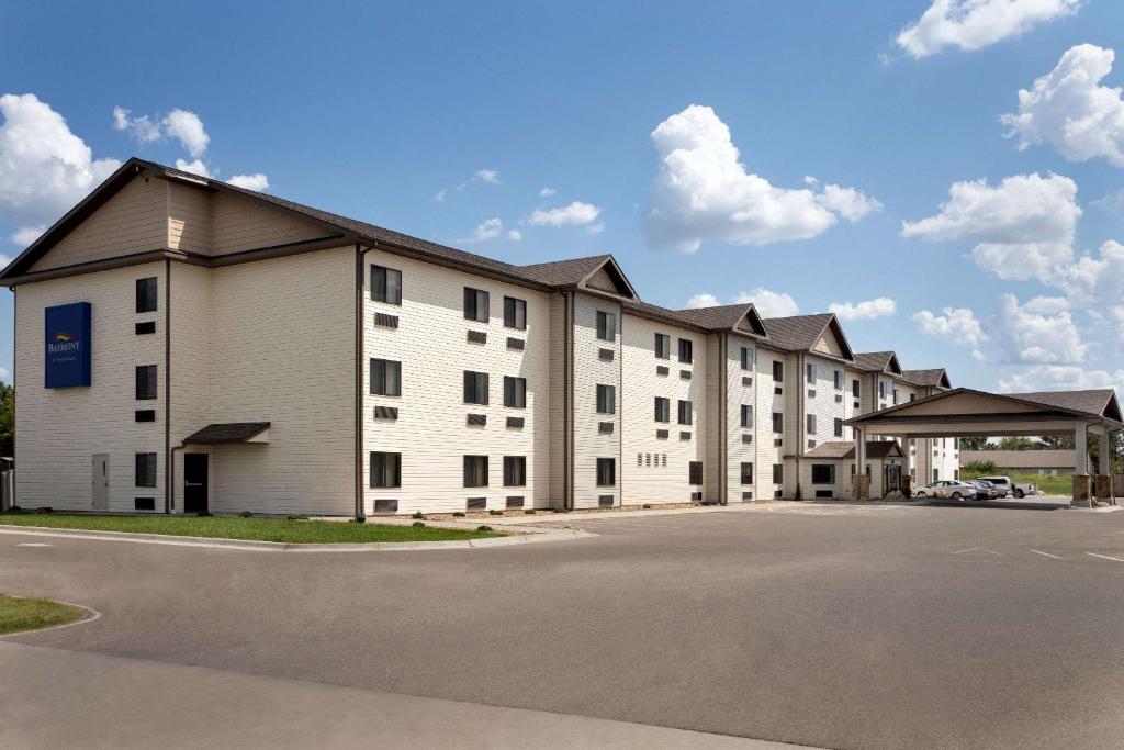 a large white apartment building with a parking lot at Baymont by Wyndham Wellington in Wellington