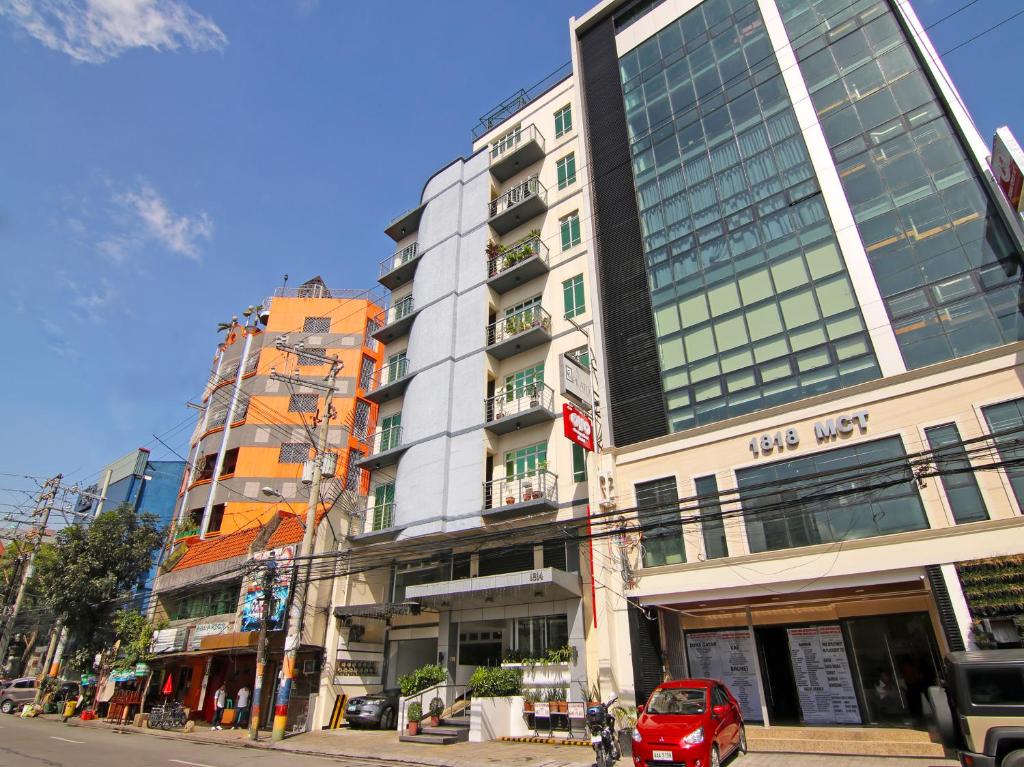 a red car parked in front of a tall building at Super OYO 107 Orange Nest Hotel in Manila