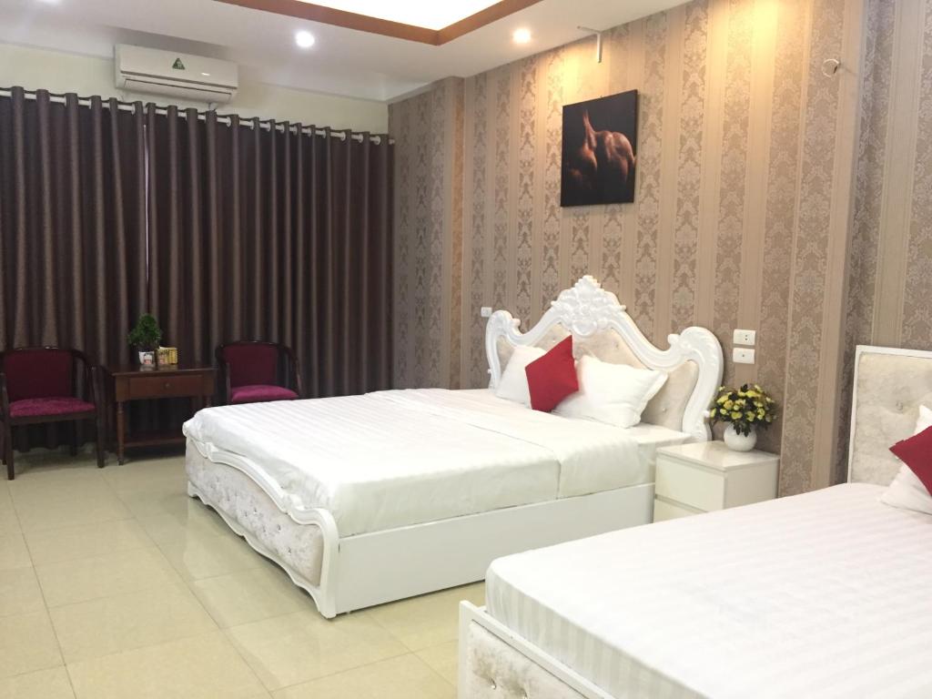 a hotel room with two beds and a chair at HD Hotel Nội Bài in Noi Bai
