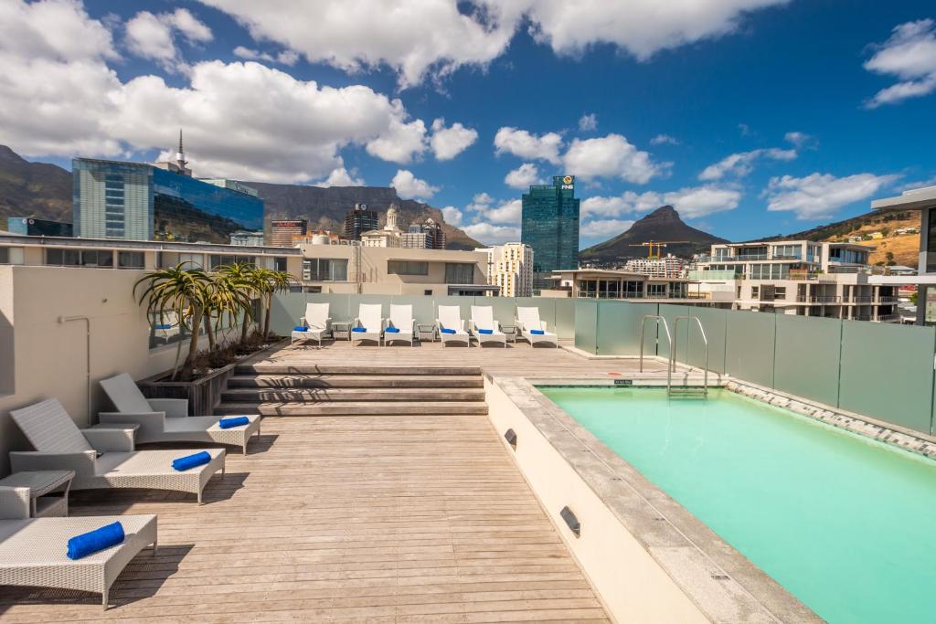 a beach with a pool, chairs, and a pool table at aha Harbour Bridge Hotel & Suites in Cape Town