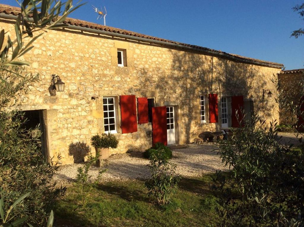 a stone house with red bows on the front of it at annexe du Mesnil in Le Tourne