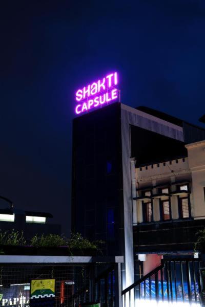 un'insegna luminosa al neon in cima a un edificio di Hotel Shakti Capsule a Bandung