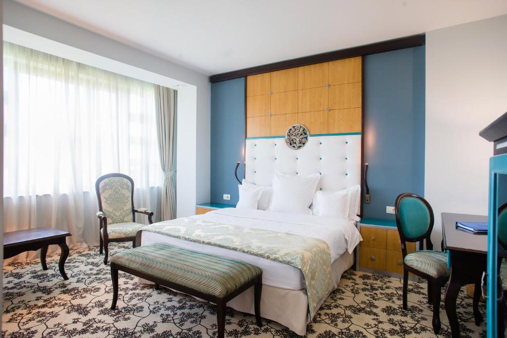 a bedroom with a bed and two chairs and a desk at Pleiada Boutique Hotel & Spa in Iaşi