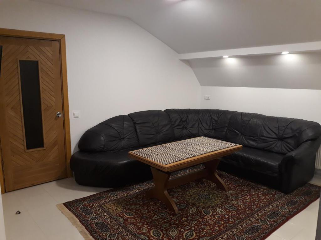 um sofá de couro preto com uma mesa de centro num quarto em Centras em Kėdainiai
