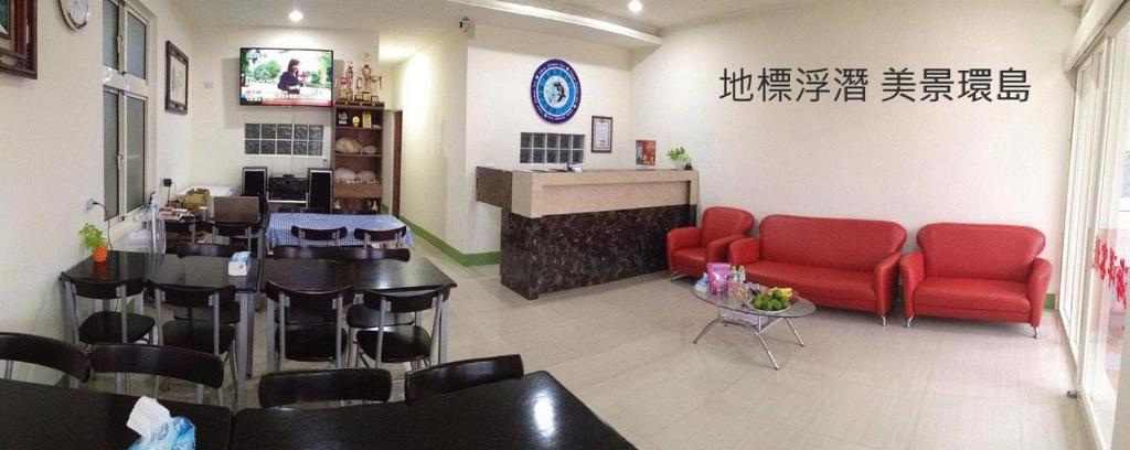 een wachtkamer met rode stoelen en een tafel en een bar bij 小琉球觀海洋客棧View Ocean Inn in Xiaoliuqiu