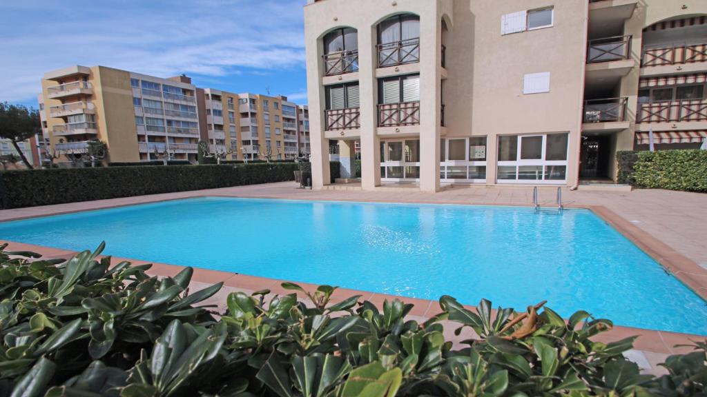 une grande piscine bleue devant un immeuble dans l'établissement Coralines, à Sainte-Maxime