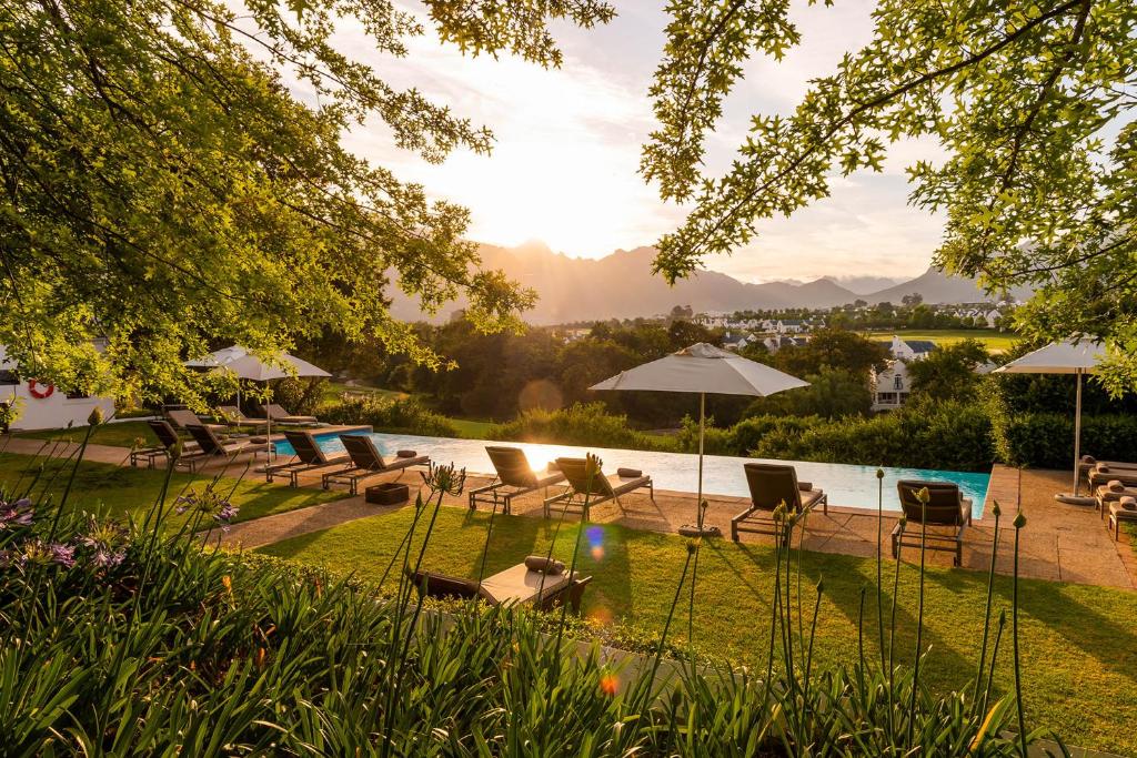 Stellenbosch的住宿－De Zalze Lodge，庭院内一个带椅子和遮阳伞的游泳池