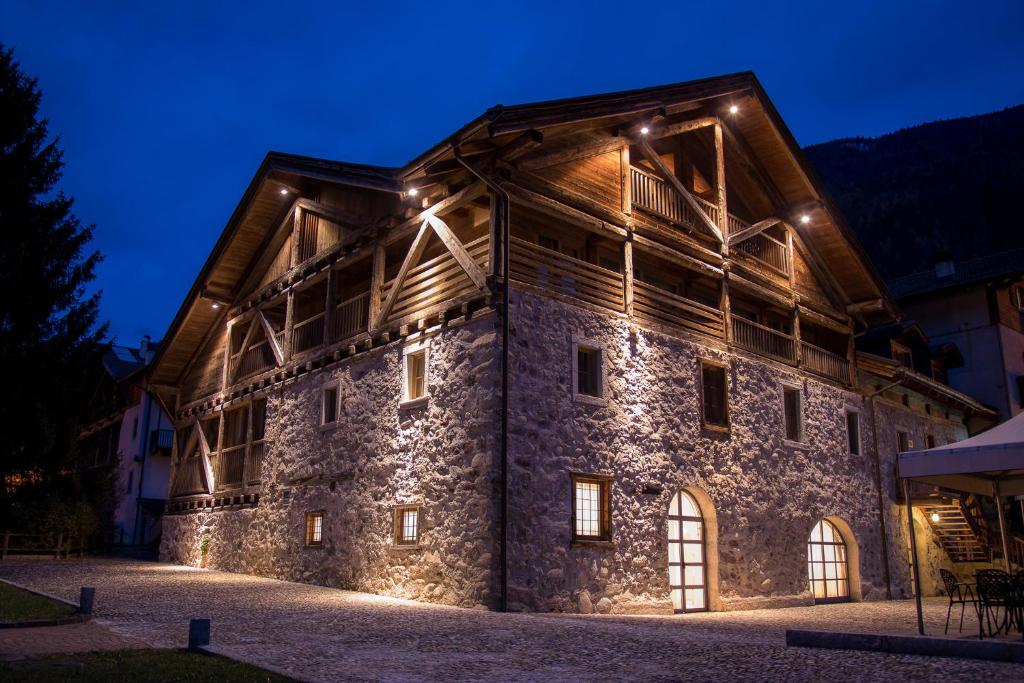 un grande edificio in pietra con luci accese di notte di Casa Moresc a Spiazzo