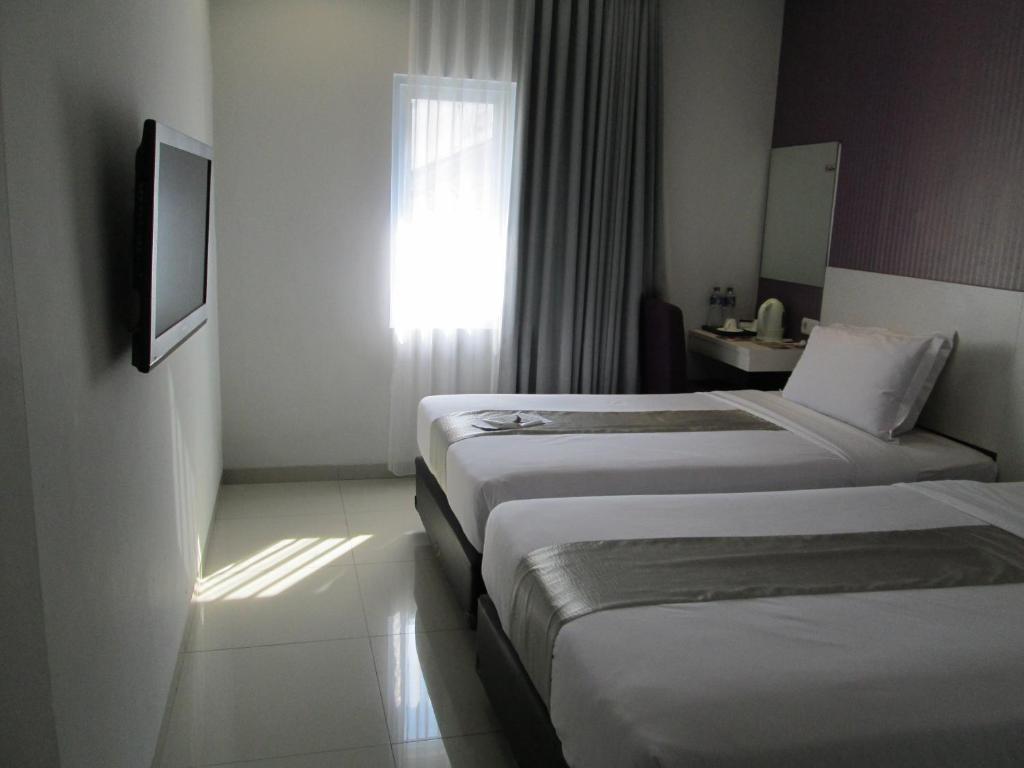 a hotel room with three beds and a window at Vio Surapati Bandung in Bandung