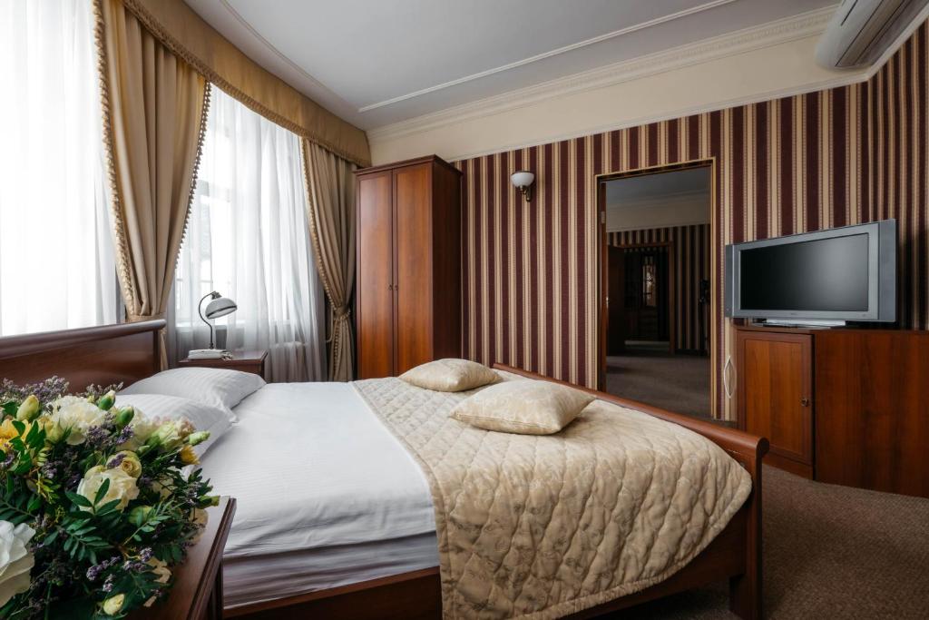 a hotel room with a bed and a flat screen tv at Tsentralny by USTA Hotels in Yekaterinburg