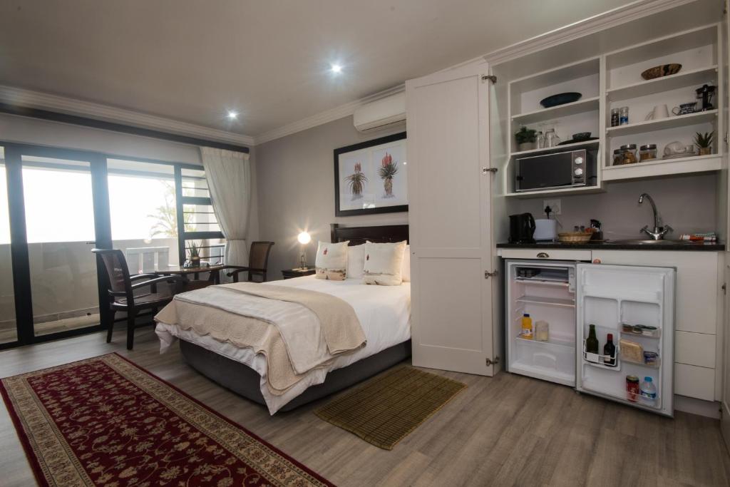 a bedroom with a bed and a kitchen and a table at Hillside Guesthouse Umhlanga in Durban