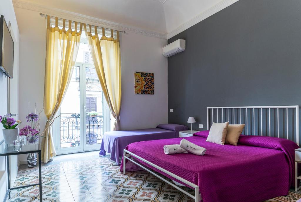 a purple bedroom with two beds and a window at C'era Una Volta in Palermo