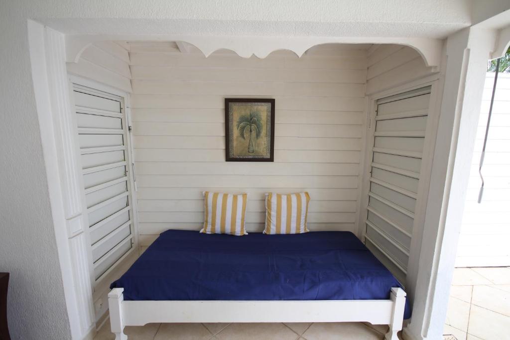 a bed in a room with white walls at Villa Les Palmiers in Saint-François
