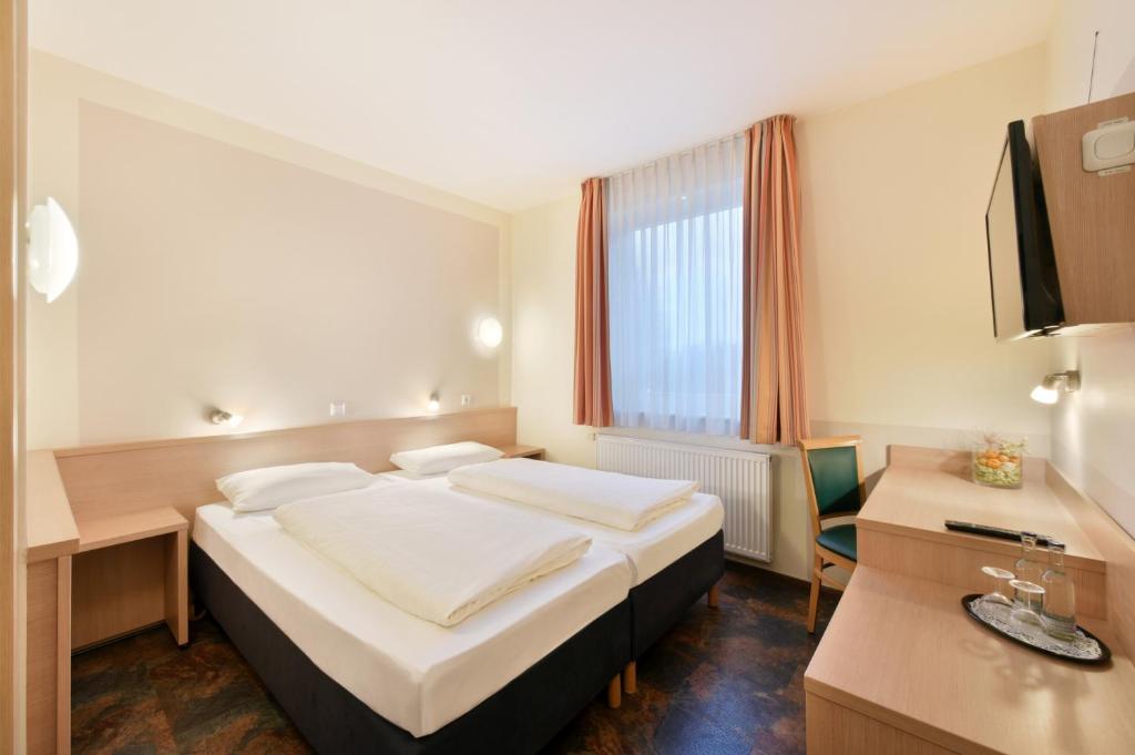 a hotel room with a bed and a desk and a tv at meinHotel in Hamburg